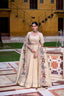 Model showcasing a premium cream organza silk Chaniya Choli featuring a clean fluid skirt, a pearl-beaded floral blouse, and a majestic sheer dupatta bordered with a colorful folk-art embroidery depicting a royal elephant procession inside a courtyard setting.