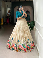 Model showcasing a premium beige silk box-pleated Chaniya Choli with a vibrant pink watercolor lotus print border and a structured deep teal blue notch collar blouse inside a boutique store setup.