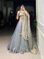 Model showcasing a premium ice blue metallic tissue silk Chaniya Choli featuring a dual-tone gold shimmer, matching sleeveless choli blouse, and a heavy scalloped gold zari border dupatta inside a boutique.