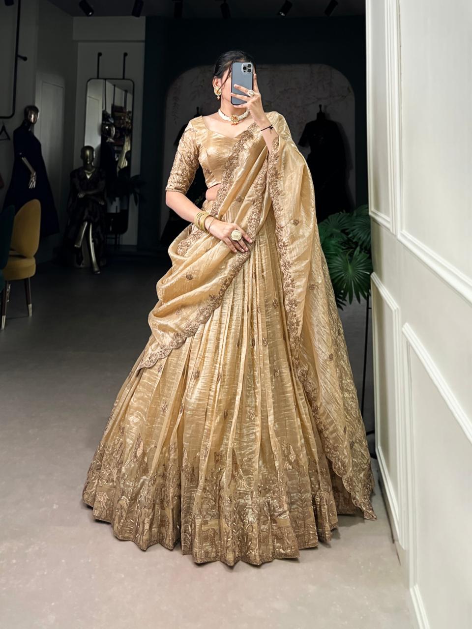 Model showcasing a premium imperial metallic gold tissue silk Chaniya Choli featuring a heavy woven gold zari border with palace arches, an elegant elbow-length sleeve choli, and a scalloped border dupatta inside a boutique. Main image