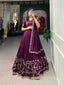 Model showcasing a premium deep wine silk Chaniya Choli featuring heavy gold zari and dori floral vine border embroidery, an intricately detailed matching mid-sleeve blouse, and a scalloped border dupatta inside a boutique showroom.