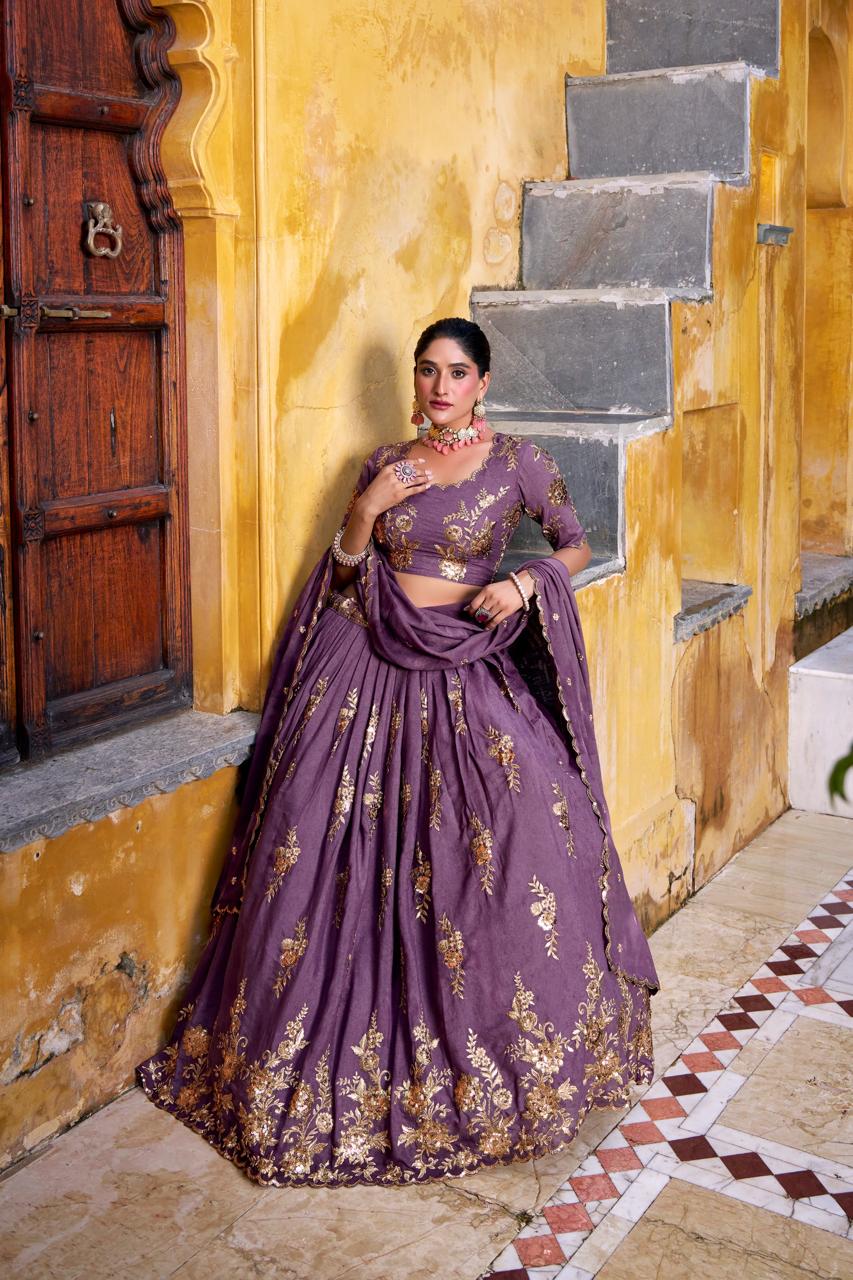 Model showcasing a premium royal mauve silk Chaniya Choli featuring heavy gold zari floral vine border embroidery, an intricately detailed matching mid-sleeve blouse, and a scalloped border dupatta inside a traditional outdoor heritage palace setting.
