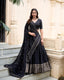 Model showcasing a premium royal midnight black cotton silk Chaniya Choli featuring a heavy woven gold zari border, an elegant V-neck elbow sleeve blouse, and an embroidered black dupatta inside a traditional architecture location.