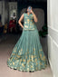 Model showcasing a premium sage green woven silk Chaniya Choli with fine gold zari floral bouquets and a matching sleeveless long tunic choli blouse inside a boutique store setup.