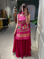 Model showcasing a premium pink Patola print long sleeveless tunic kurti with a heavy hand-embroidered royal elephant motif panel and a matching flared solid pink sharara pant inside a boutique.
